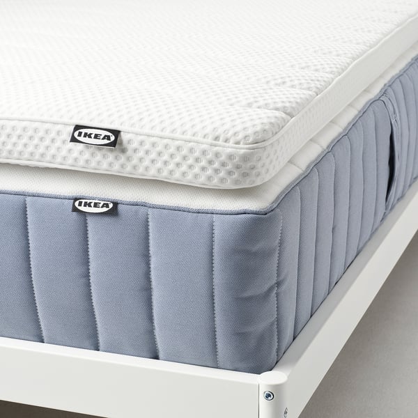 Colchão Ikea, tampo branco, laterais cinza, em moldura branca. Espuma macia para conforto e alívio de pressão.