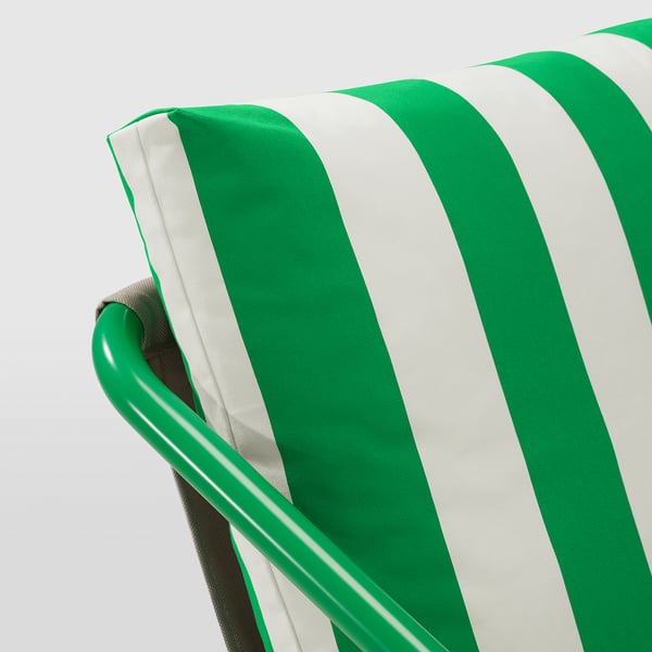 Uma almofada listrada verde e branca em uma cadeira moderna, destacando design de qualidade e conforto.