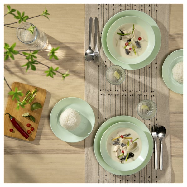 Pratos de vidro verde com comida, utensílios e decoração.