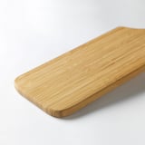 Tábua de corte de bambu retangular lisa em uma superfície branca.