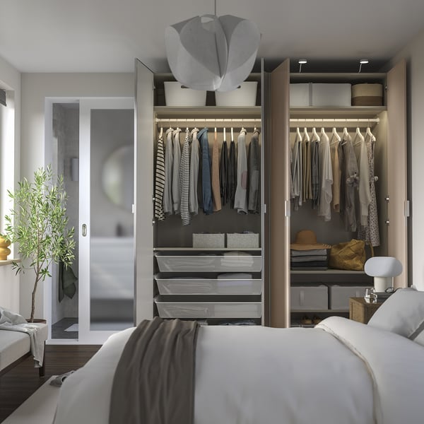Quarto moderno com guarda-roupa aberto mostrando roupas, acessórios e prateleiras iluminadas. Dobradiças de fechamento suave visíveis, iluminação integrada nas prateleiras.