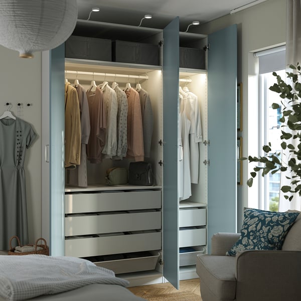 Um quarto moderno com um guarda-roupa aberto exibindo roupas em cabides, gavetas e luzes led no interior.