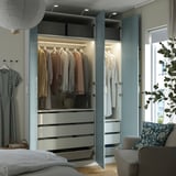 Um quarto moderno com um guarda-roupa aberto exibindo roupas em cabides, gavetas e luzes led no interior.