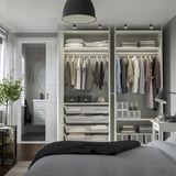 Quarto com roupeiro PAX, roupa organizada, prateleiras e gavetas, incluindo espaço para pendurar e cestos de arrumação.