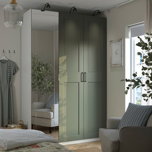 Quarto moderno com guarda-roupa PAX verde e portas espelhadas, cercado por uma cadeira cinza, cama e planta.
