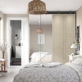 Quarto aconchegante com roupa de cama florida, guarda-roupas grandes e banheiro aberto.