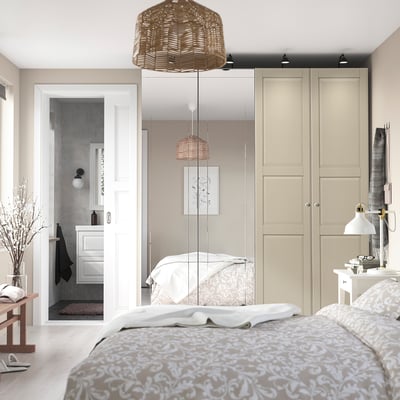 Quarto aconchegante com roupa de cama florida, guarda-roupas grandes e banheiro aberto.