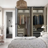 Quarto moderno com armário aberto mostrando roupas, gavetas e prateleiras dentro.
