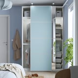Um guarda-roupa moderno com portas de correr e várias prateleiras, arrumação de roupas e acessórios, com iluminação visível no interior.