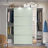 Um guarda-roupa moderno com portas de correr revela cabides segurando casacos e roupas. A iluminação interna ilumina o espaço organizado.