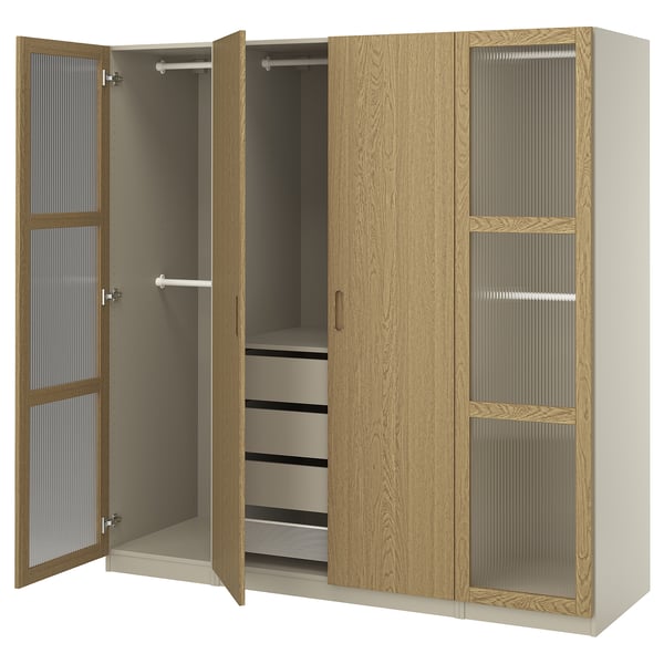 Um guarda-roupa de madeira aberto chamado PAX com prateleiras e cabides. Tem um acabamento em carvalho castanho claro e inclui gavetas e portas de vidro.