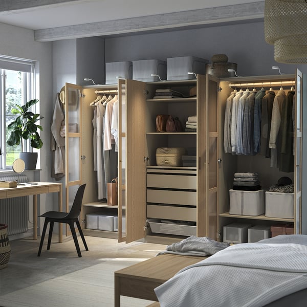 Closet organizado com cabides, prateleiras, gavetas e caixas de armazenamento. Iluminação embutida e pés ajustáveis.