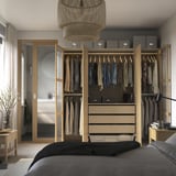 Quarto moderno com grande guarda-roupa de madeira, portas de vidro e interior organizado.