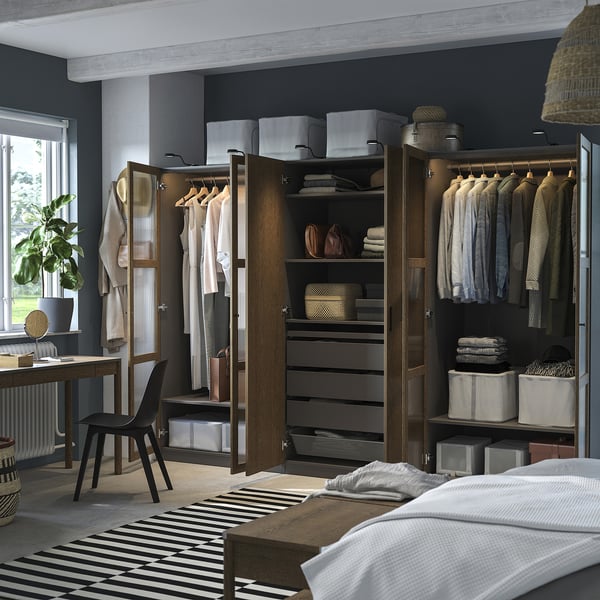 Quarto moderno com guarda-roupas abertos exibindo roupas, itens dobrados e caixas de armazenamento. Os guarda-roupas têm trilhos e prateleiras para organização.