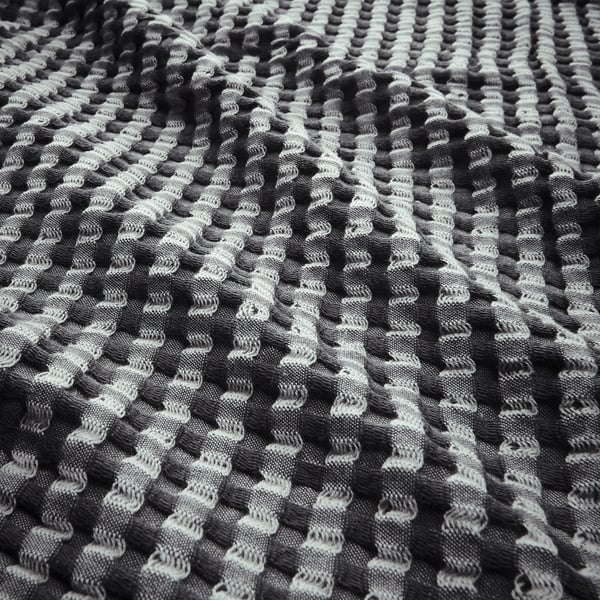 Colcha de tecido waffle preto e branco, texturizada, reversível, confeccionada em 100% algodão.