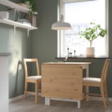 Mesa de abas rebatíveis PINNTORP com 2 cadeiras, luminária pendente e prateleiras.