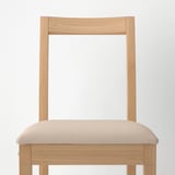 Cadeira leve de madeira com almofada bege, resistente e moderna, ideal para refeições.