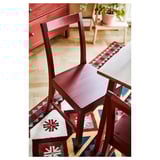 Cadeiras de jantar de madeira vermelha e configuração de mesa em tapete colorido.