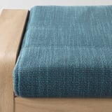 Um repousa-pés acolchoado azul sobre base de madeira, concebido para conforto e relaxamento.