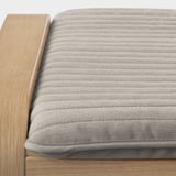 Close-up da almofada POÄNG na cadeira de madeira, mostrando textura e costura de qualidade.