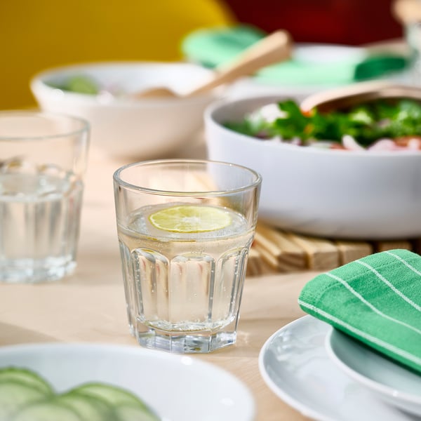 Copo de vidro transparente com fatia de limão, parte da série POKAL. Resistente, seguro para lavar louça, perfeito para bebidas refrescantes.