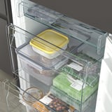 Uma geladeira moderna com prateleiras de vidro ajustáveis transparentes exibindo vários itens alimentares, como um recipiente amarelo, nozes e produtos verdes embalados.