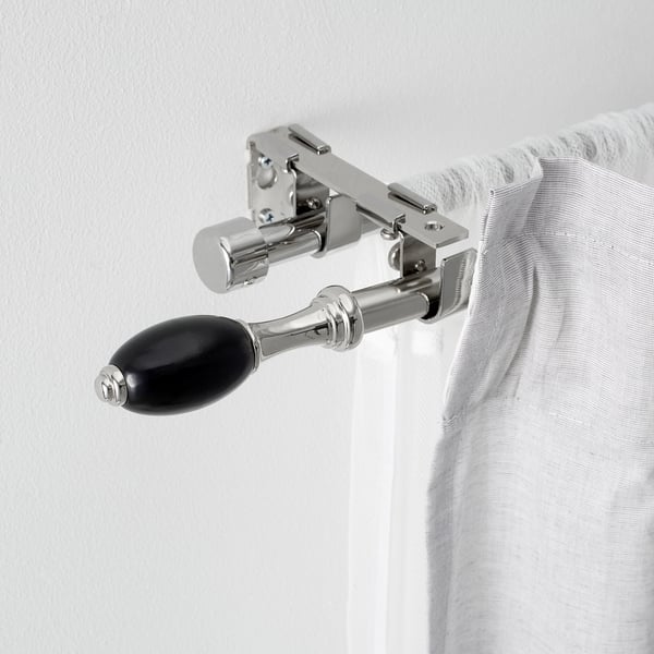 Ferragens modernas para varão de cortina com metal polido e detalhes em preto, segurando com segurança uma cortina branca, exibindo um design elegante e sofisticado.