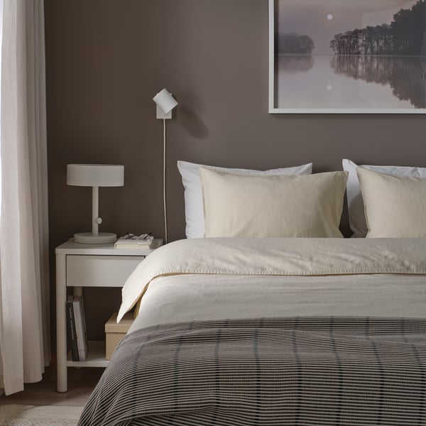 Quarto cinzento com cama RUNDHAGTORN, criado-mudo, candeeiro, livros, arte de parede, cortina.