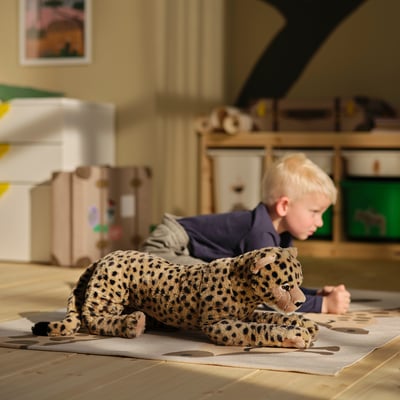 Brinquedo de chita de pelúcia, bege com manchas pretas, design macio e realista, posição agachada, feito de poliéster reciclado.