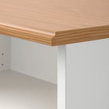 Grande plano da borda do banco de TV SKRUVBY: tampo liso com acabamento em carvalho e borda perfilada, painel lateral branco.