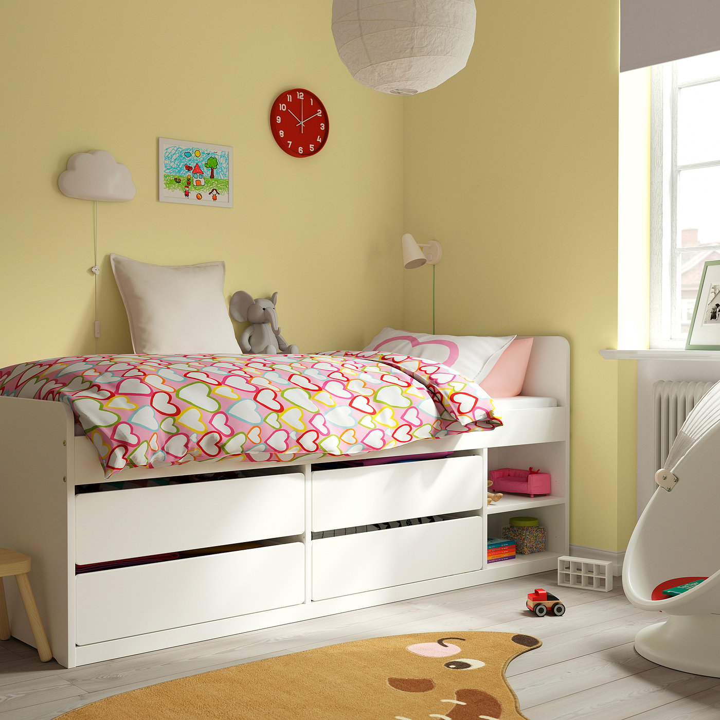 Quarto aconchegante para crianças com cama com padrão de coração, brinquedo de elefante, relógio vermelho, lâmpadas de nuvem, tapete de urso e cadeira de balanço.