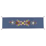 Um caminho de mesa azul bordado à mão com desenhos florais coloridos. É retangular com extremidades franjadas e feito de algodão.
