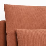 Close-up de uma chaise longue de veludo cotelê marrom-avermelhado, exibindo seu tecido texturizado de alta qualidade e design confortável.