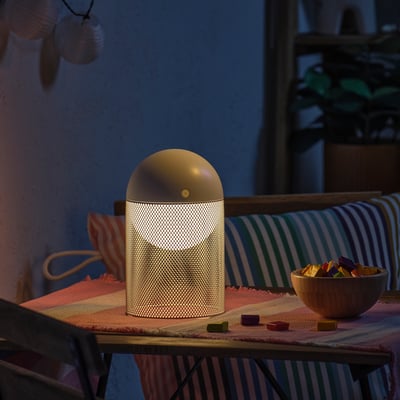 Candeeiro SOLVINDEN moderno sobre mesa de madeira com snacks, interior/exterior.