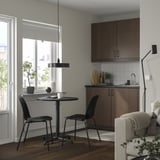 Cozinha moderna com armários escuros, mesa STENSELE, cadeiras e sofá com vista panorâmica.