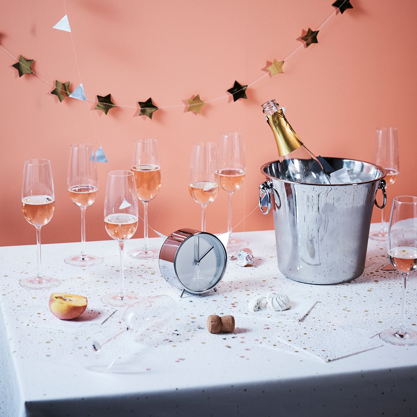 Taças de champanhe e balde de gelo na mesa, decorados com guirlanda de estrelas.