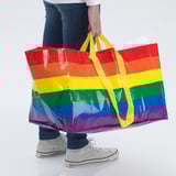 Pessoa segurando uma grande bolsa listrada de arco-íris; Ideal para transportar e armazenar vários itens.