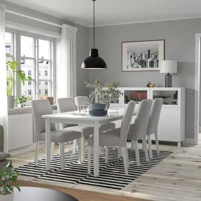 Sala de jantar moderna com mesa extensível para seis pessoas, candeeiro preto, tapete às riscas, janela com vista para a cidade.