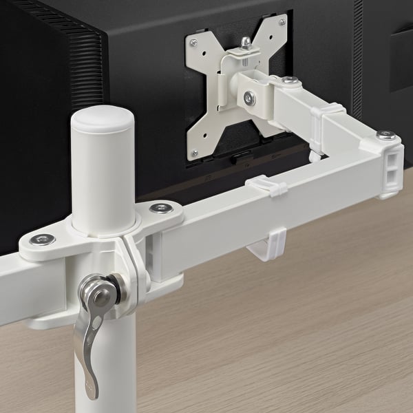 Braço de monitor branco montado na mesa, segurando com segurança o monitor preto, com juntas ajustáveis e clipes anexados para gerenciamento de cabos.