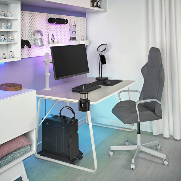 Escritório em casa com monitor STUBBERGET, cadeira gamer, paredes coloridas e prateleiras de brinquedos.