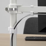 Braço de monitor ajustável montado na mesa com grampos STUBBERGET brancos, cabos bem organizados.