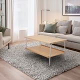 Sala de estar moderna com mesa de café cinza e madeira clara, tapete estampado, sofá e cortinas combinando.