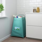 Saco de armazenamento de brinquedos verde TIGERFINK no quarto com armário branco, frascos com estampa de leopardo e planta. Contém vários brinquedos infantis.