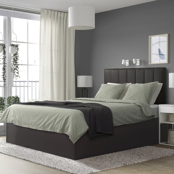 Quarto moderno com cama TJÅLLE, paredes escuras, janela grande e plantas.