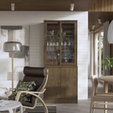 Sala de estar moderna com parede de tijolos brancos, armário TONSTAD, poltrona reclinável, candeeiro de pé, mesa de jantar e janela com cortinas.