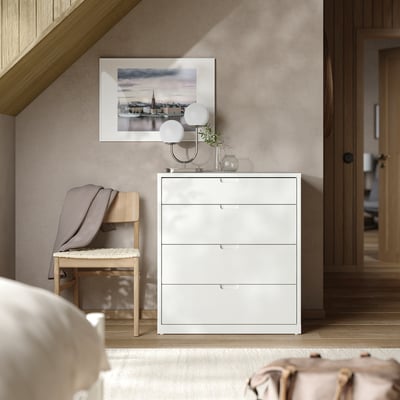 Quarto moderno com baú branco TONSTAD, banco de madeira, luminária e arte emoldurada.