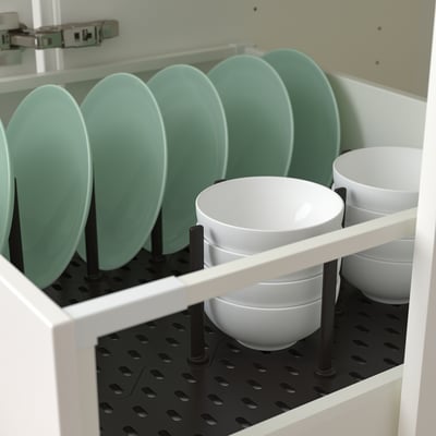 Armário branco com pratos verdes e tigelas brancas organizadas por pinos ajustáveis.