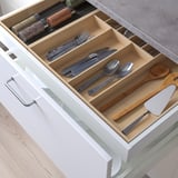 Gaveta de cozinha organizada com compartimentos para talheres e utensílios.