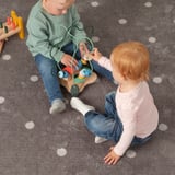 Duas crianças brincam com um labirinto de contas, aprendendo formas e cores.