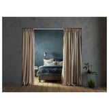 Um quarto aconchegante com uma cama cinza, cortinas marrons claras e mesas laterais verdes.